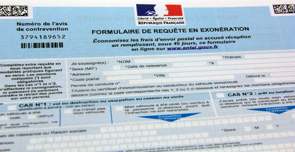 Des mains tapent sur un clavier d'ordinateur avec un formulaire administratif papier posé à côté, dans un environnement de bureau classique